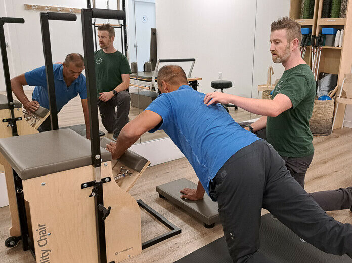 Kinesiologist Alfred Ball teaches a client Clinical Pilates. Exercises improve core strength to reduce low back pain.